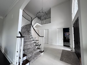 Elegant foyer with a spiral staircase, chandelier, and modern interior design, showcasing a bright and spacious entryway for residential interior painting services by GetPro Painting in Canton, MI.