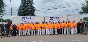 GetPro Painting team in matching orange shirts standing in front of company trucks, showcasing professionalism and teamwork in painting services.