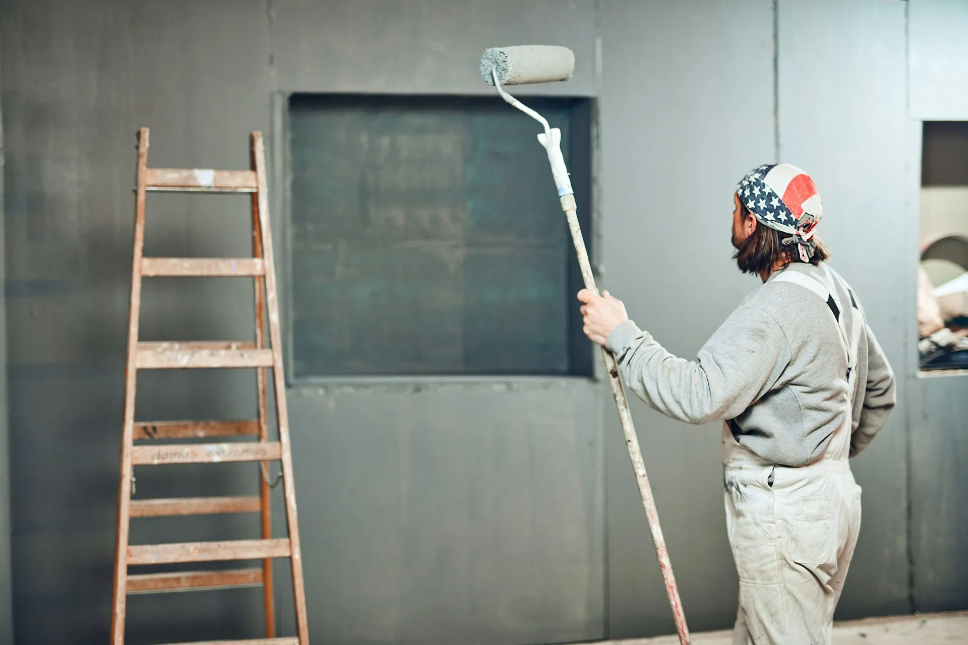 Painter on ladder applying primer to metal wall panel