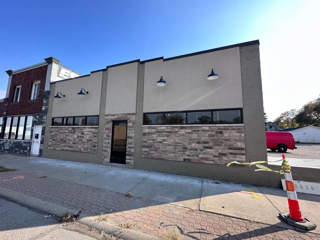 Modernized commercial building with stone and stucco, black windows, and gooseneck lights.