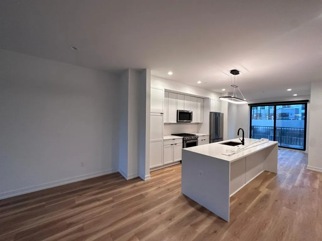 Modern kitchen with white cabinetry, stainless steel appliances, and a large island.