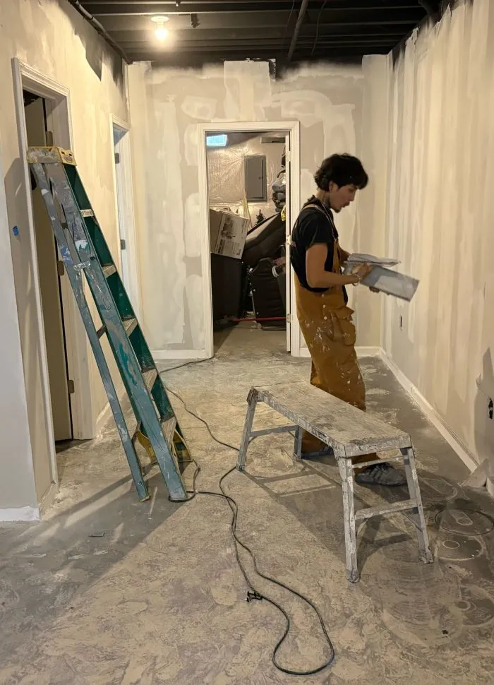 Painter prepping interior room with ladder before painting